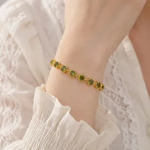 Elegant 18k gold plated bracelet featuring round green zircons on a female model's wrist