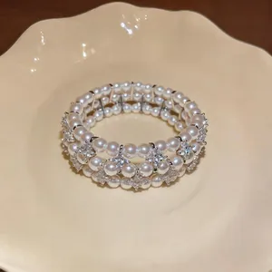 Vista dettagliata di un elegante bracciale di perle multistrato con accenti di strass