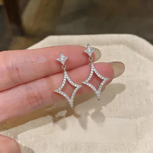 Detailed macro shot of elegant sparkling zircon star-shaped drop earrings with 18k gold plating.