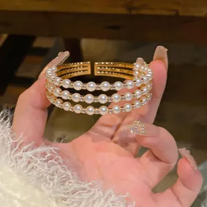 Vista dettagliata di un elegante bracciale a tre strati in oro con perle e strass