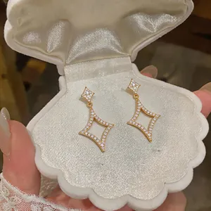 Close-up of sparkling zircon star earrings in a white shell-shaped jewelry box