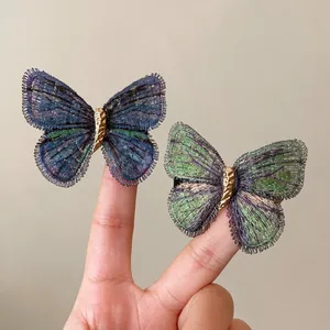 Vintage iridescent knitted butterfly hair clips shown on fingers for size reference