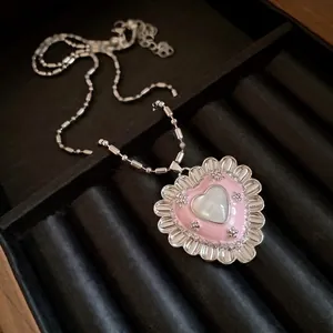 Vintage style pink heart pendant necklace with cat eye stone on black velvet background.