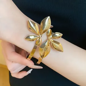Detailansicht eines goldenen doppellagigen Blatt-Armreifs am Handgelenk einer Frau