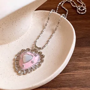 Vintage heart pendant necklace with pink enamel and cat's eye stone on ceramic dish