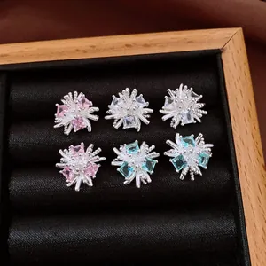 Primo piano di orecchini a fiore scintillanti con zirconi rosa e blu in scatola