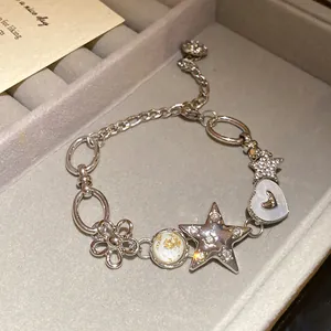 Close-up of elegant silver bracelet featuring rhinestone flower, star and heart charms.