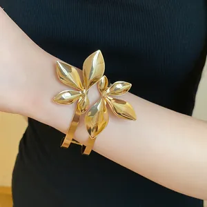 Nahaufnahme eines goldenen Armreifs mit elegantem Doppelblatt-Design am Handgelenk.