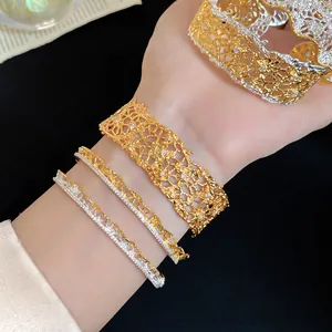Detailed macro shot of elegant gold and silver lace textured open bracelets on a model arm