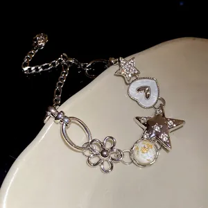 Close-up of a silver charm bracelet with rhinestone stars, hearts and flowers