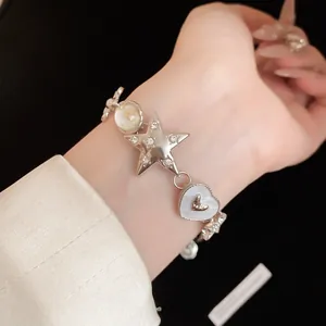 Close-up of silver charm bracelet featuring rhinestone star and heart details