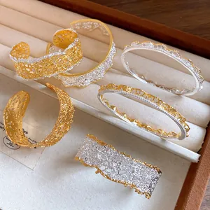 Detail view of French style lace texture open bangles in gold and silver finish
