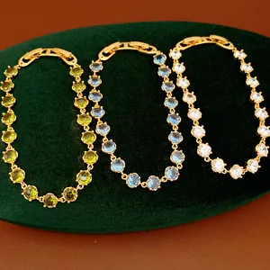 Detail shot of three 18k gold plated bracelets with green, blue, and clear round zircons.