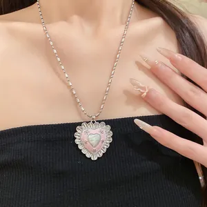 Close-up of vintage heart pendant necklace with pink enamel and cat-eye stone