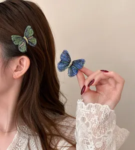 Close-up of delicate vintage embroidered butterfly hair clips shown on hair and held by hand
