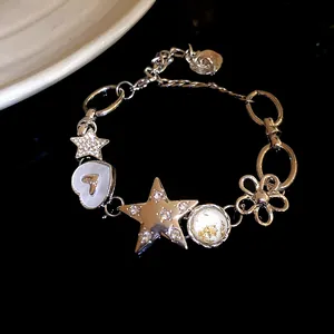Close-up detail of silver charm bracelet with rhinestone stars and flower pendant