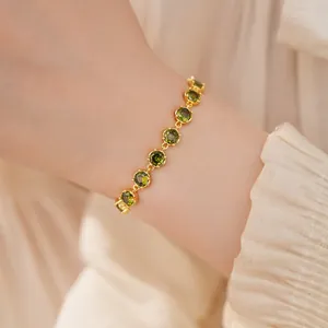 Close-up view of an elegant olive green zircon bracelet with 18k gold plating on a wrist