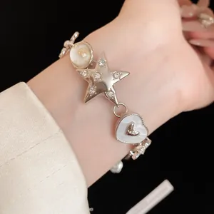 Close-up view of a sparkling star and heart charm bracelet on a model's wrist.