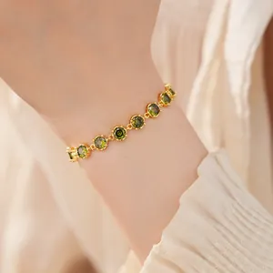 Detail view of a 18k real gold-plated bracelet featuring green zircon round stones on a wrist