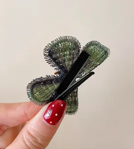 Detail view of the black duckbill clip on a green knitted butterfly hair accessory