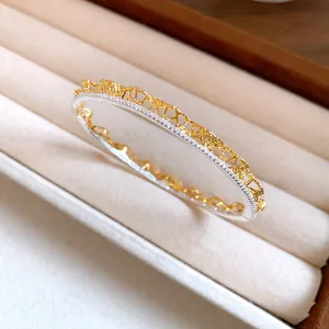 Close-up detail of a gold lace texture bangle with sparkling crystals in a velvet tray