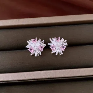Primo piano dettagliato di orecchini a lobo a fiore in argento con zirconi rosa.