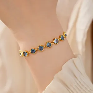 Close-up of 18k gold plated bracelet with round blue stones on a wrist