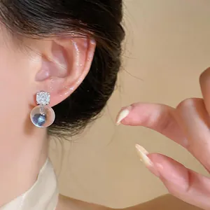 Close-up of French style silver needle earring with sparkling stone and resin sphere