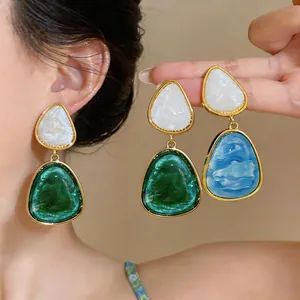 Vista dettagliata di orecchini a pendente geometrici in resina vintage verde e blu