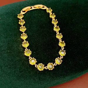 Close-up of elegant 18k gold plated bracelet featuring vibrant round green zircons