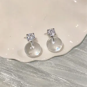Close-up of elegant French style earrings with cubic zirconia and clear resin balls