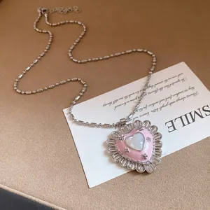 Close-up detail of vintage heart pendant necklace with pink enamel and cat eye stone