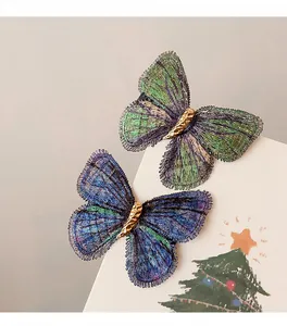 Detailed view of iridescent embroidered butterfly hair clips featuring a gold textured center