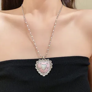 Detail view of a vintage heart necklace with pink enamel and cat-eye stone on model.