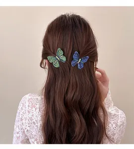 Detailed view of knitted butterfly hair clips in green and blue on brown hair