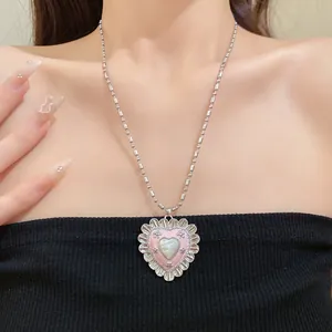 Close-up of vintage heart pendant necklace with pink enamel and cat-eye stone on model neck