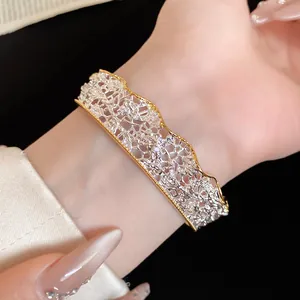 Detailed view of a gold and silver lace textured cuff bracelet with sparkling crystal accents