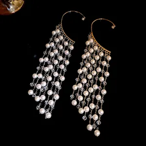 Macro view showing the intricate pearl tassel and crystal detail on these gold ear cuffs.
