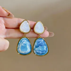 Dettaglio macro di orecchini vintage in resina con eleganti trame marmorizzate blu.