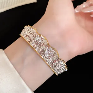 Close-up of gold and silver lace textured bangle with shimmering diamond accents.