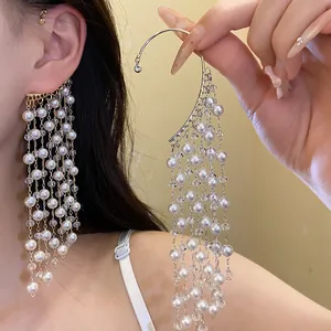 Macro detail of an elegant vintage-style long pearl tassel ear cuff with crystal accents.