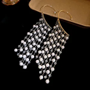Close-up of long pearl tassel ear cuffs with golden hooks and shimmering crystal beads