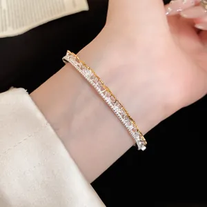 Close-up view of a silver and gold lace textured bangle with sparkling stones
