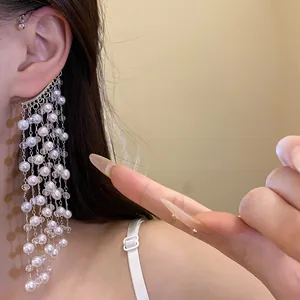 Detailed view of elegant silver ear cuff with long pearl and crystal tassels on model