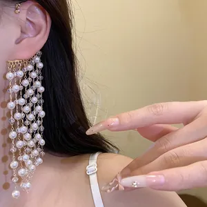 Detailed view of elegant white pearl tassel ear cuff with long vintage gold chains