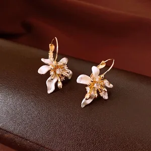 Boucles d'oreilles florales avec pétales en émail blanc et zircons étincelants.
