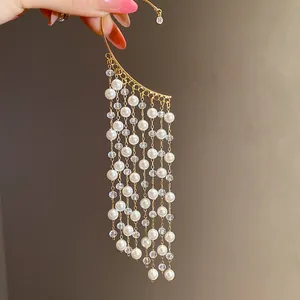 Detailed close-up of a vintage-style gold ear cuff with long pearl and crystal tassels