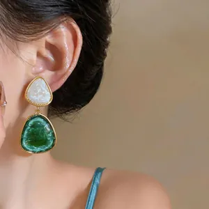 Primo piano di orecchini geometrici vintage in resina verde e bianca su una modella