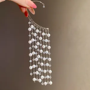 Close-up of vintage-style silver ear cuff with elegant cascading pearl tassels
