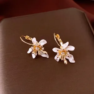 Boucles d'oreilles fleurs dorées avec pétales en émail blanc et zircons brillants.